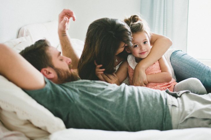 hombre y mujer acostados con niña 