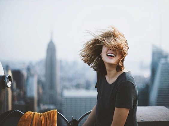 Muchacha sonriendo mientras el cabello le cubre la cara. 