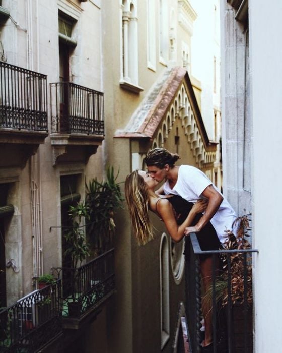 Pareja besándose en un balcón. 