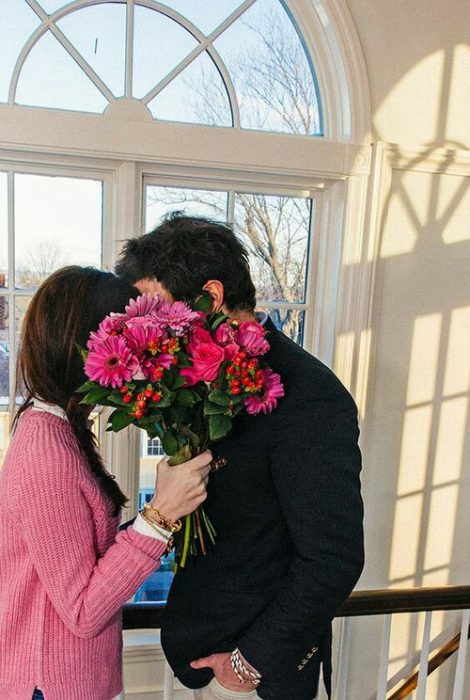 Pareja escondidos tras un arreglo floral. 