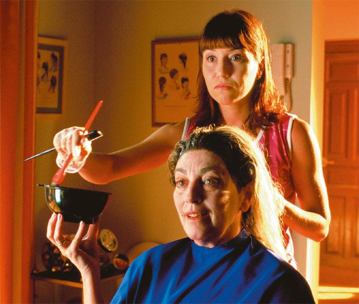 Mujer pintando el cabello de otra 
