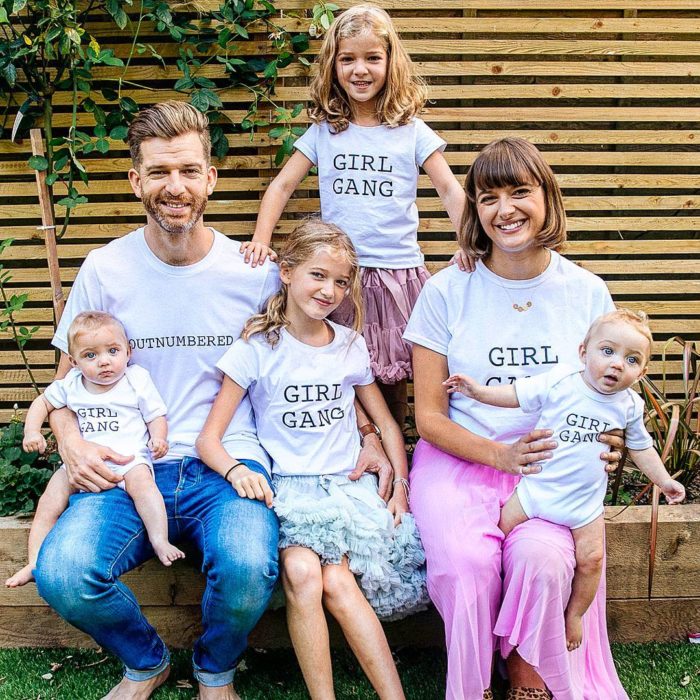 hombre y mujer junto a niñas con playeras blancas 