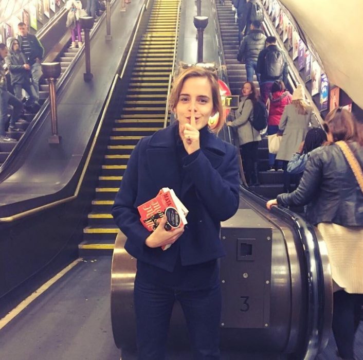 mujer con libros pone su dedo en la boca 