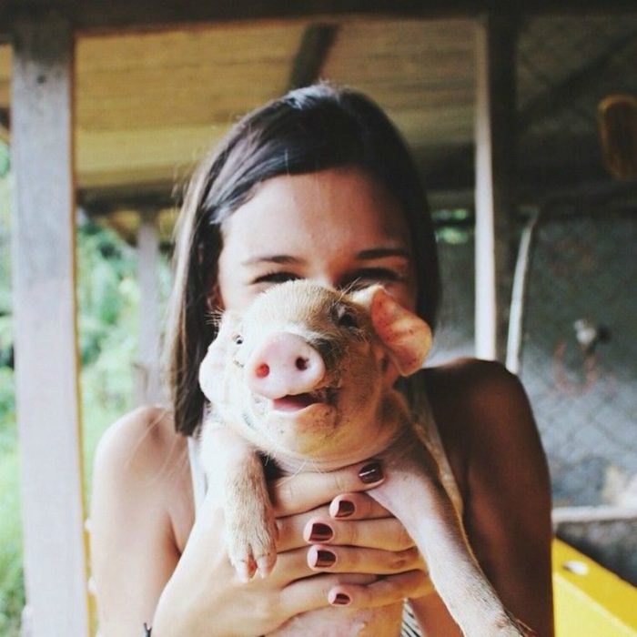 mujer cargando a un puerco pequeño 