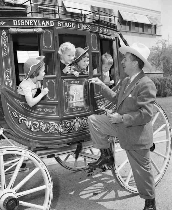 walt disney disfrutando de un paseo junto a los asistentes al parque 