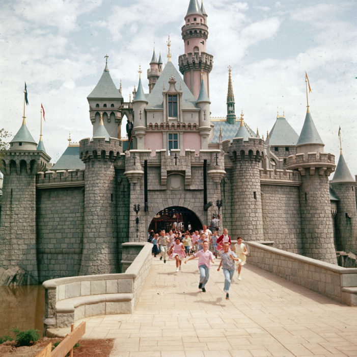 Niños corriendo por la entrada del castillo de la bella durmiente para entrar a disneyland