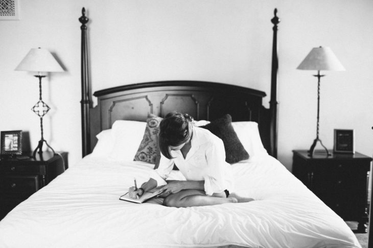 Chica sentada en la cama escribiendo sobre una libreta