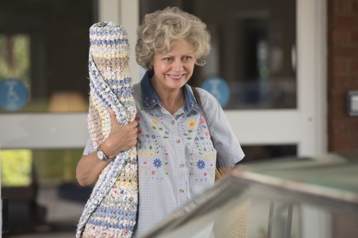 mujer anciana con alfombra enrollada 