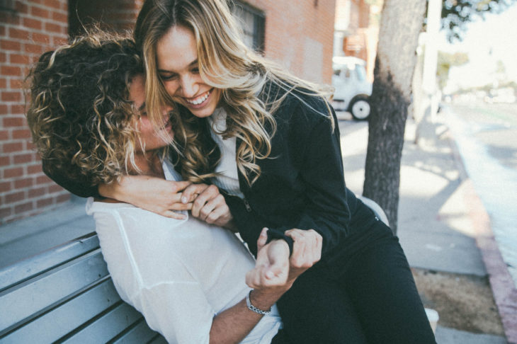 Pareja sentada en una banca riendo 