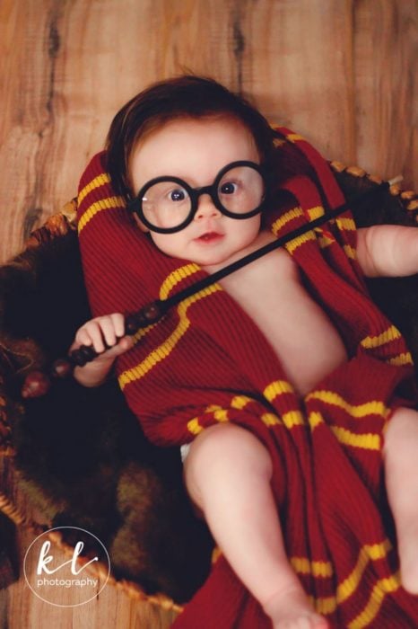 Bebé posando con una varita mágica en una sesión al estilo Harry Potter