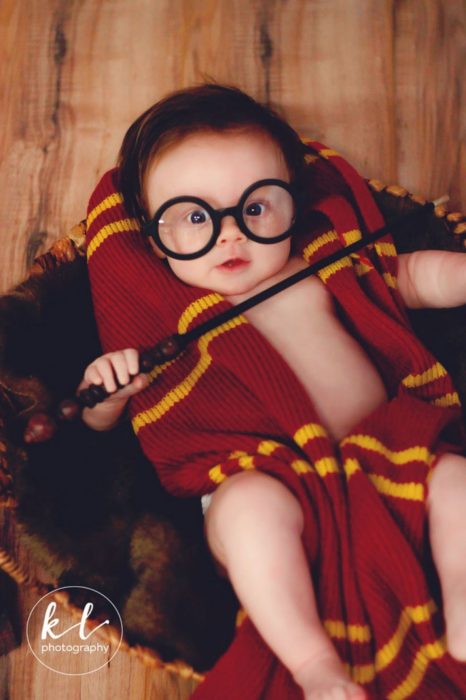 Bebé posando con una varita mágica en una sesión al estilo Harry Potter