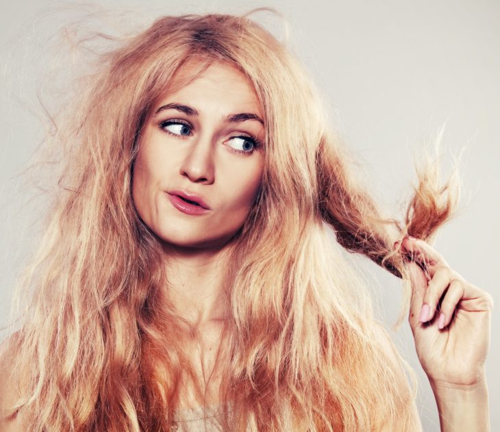 Chica observando las puntas de su cabello 