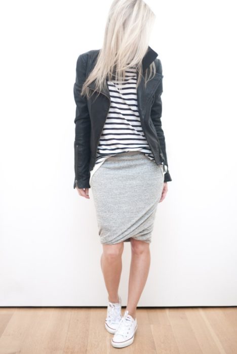 Chica usando una falda gris, blusa rayada y chaqueta de piel 