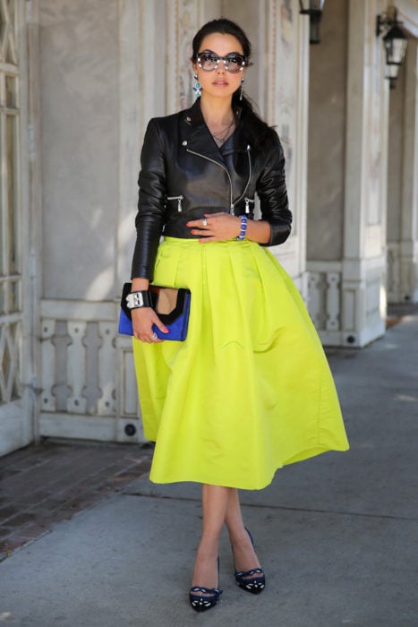 Chica usando una falda de color amarillo y una chaqueta de color negro 
