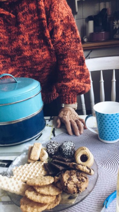 mujer anciana con galletas y café en la mesa 