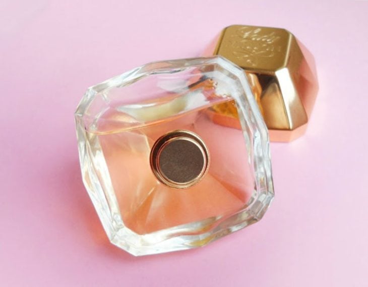 perfume dorado en mesa rosa 