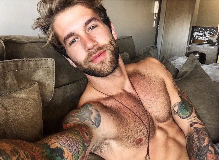 hombre sin playera con tatuajes y collar 