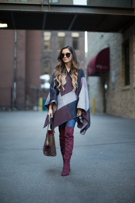 Chica usando un poncho, jeans y botas altas