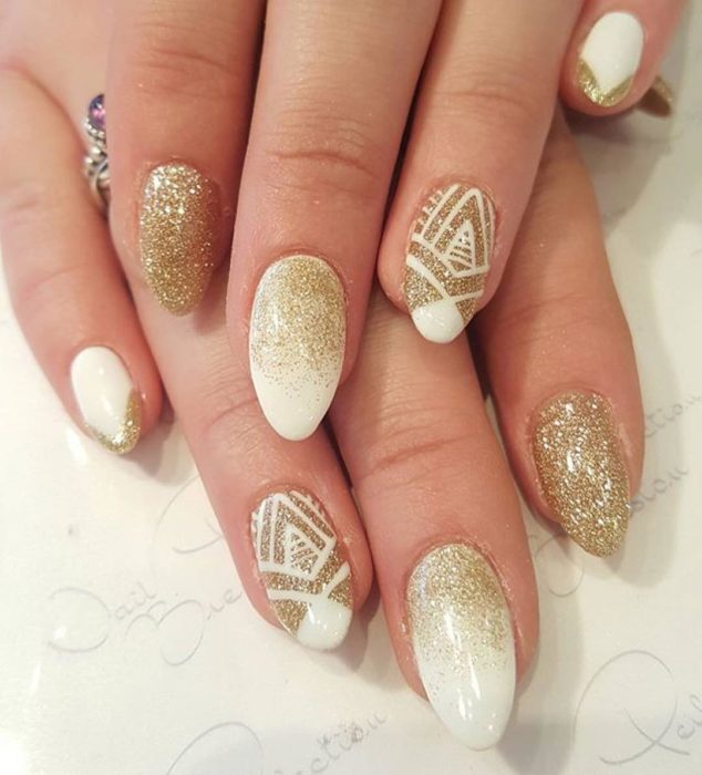 manos de mujer con uñas blancas y dorado 