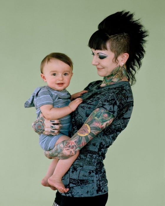 Mmá llena de tatuajes sosteniendo a su bebé en brazos