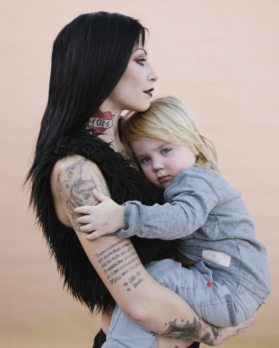 Chica con tatuajes sosteniendo a un bebé en brazos 