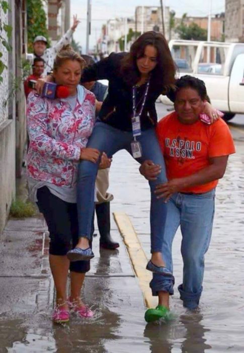 hombre y mujer cargan a una chica entre charcos de agua 