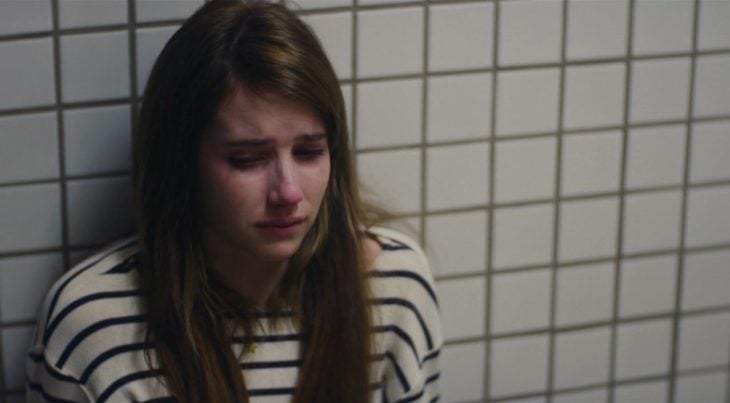 Chica recargada en la pared llorando