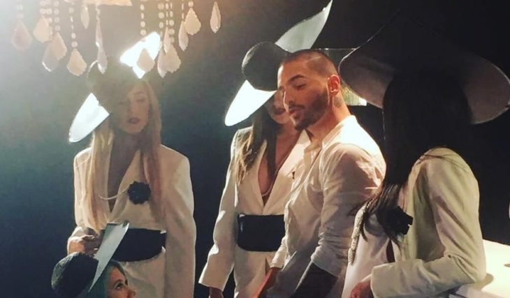 hombre con saco blanco al lado de mujeres con sombreros grandes 