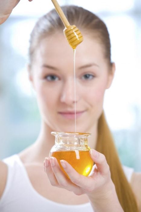 Chica aplicando miel sobre su rostro 
