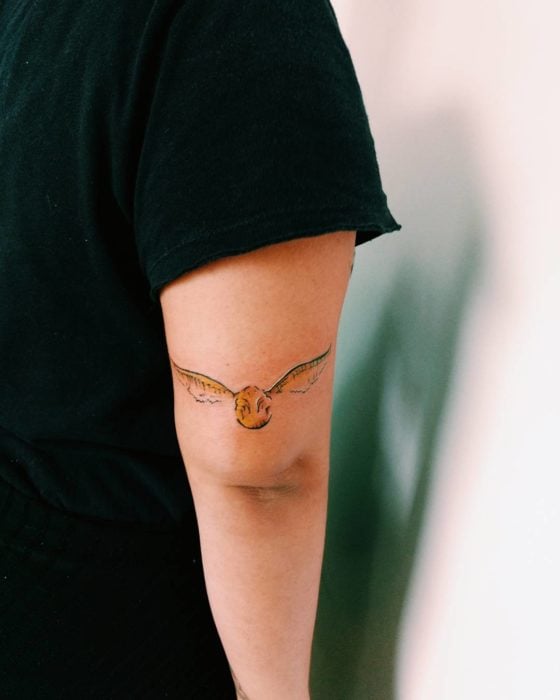 Tatuaje de una Snitch dorada en el brazo 