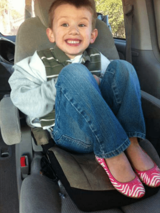 niño rubio sonriendo con zapatos rosas 