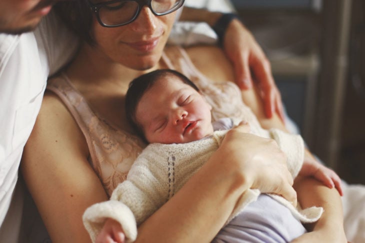 mujer con lentes abrazando a su bebé 