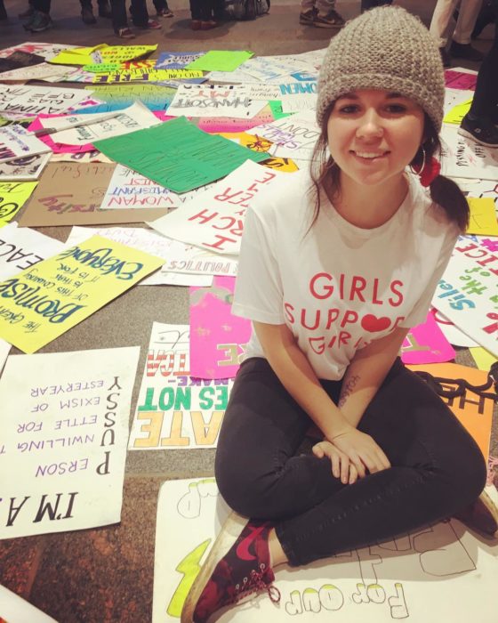 chica sentada en el piso con pancartas 
