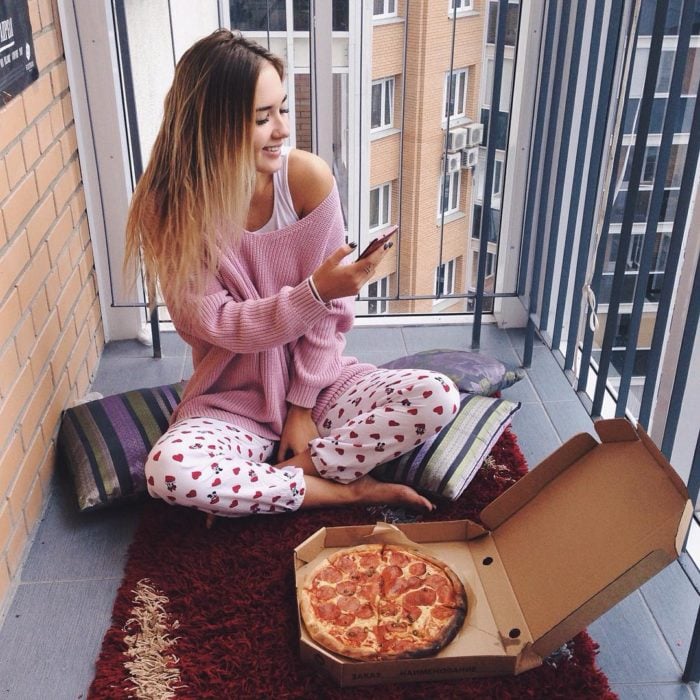 chica en pijama comiendo pizza