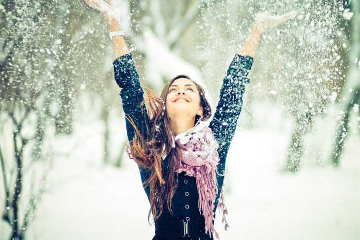 mujer feliz avienta nieve hacia arriba