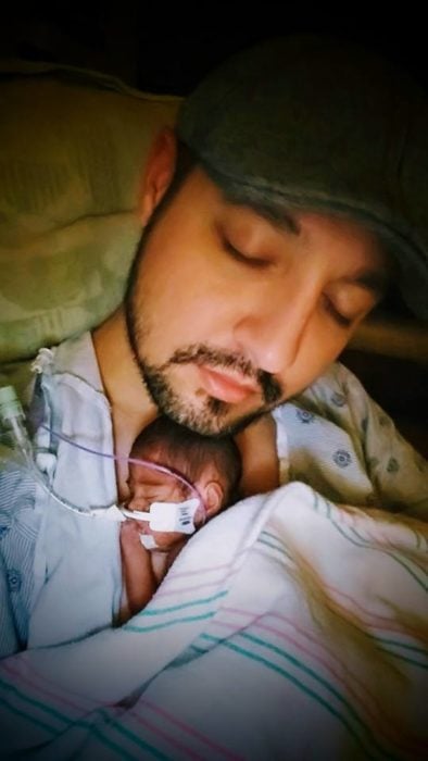 Hombre sosteniendo a su bebé prematuro en brazos 