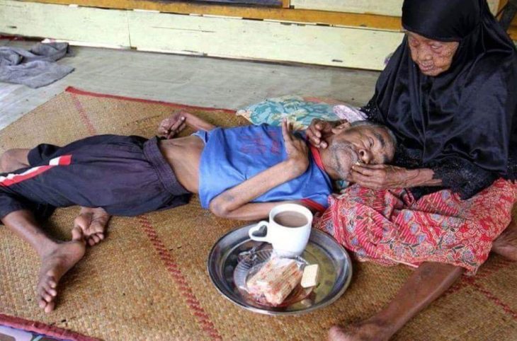 mujer anciana le da de comer a hombre 