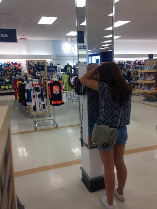 Chica apretando sus granitos frente al epejo de una tienda departamental