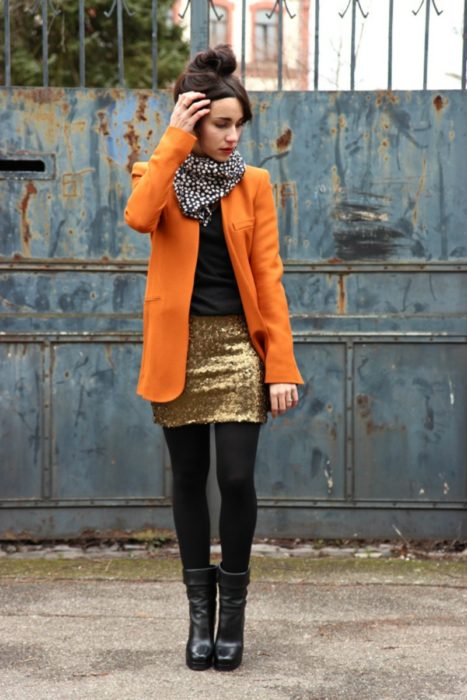 chica con falda de lentejuelas y abrigo naranja 