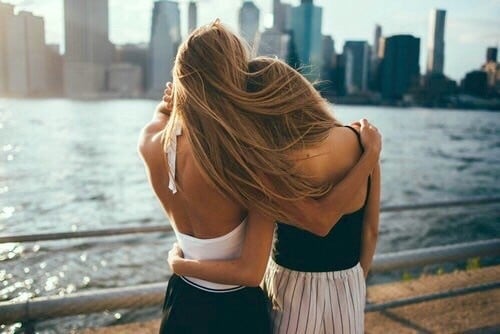 Chicas abrazadas mientras miran el mar