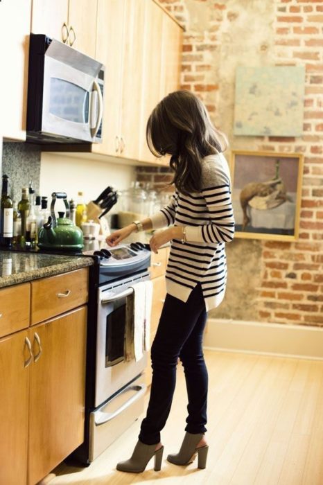 chica cocinando con pantalón negro y blusa de rayas