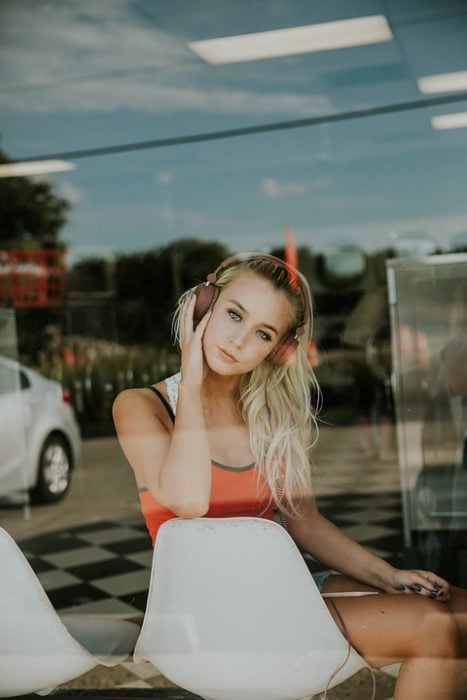 chica escuchando música sentada en silla blanca