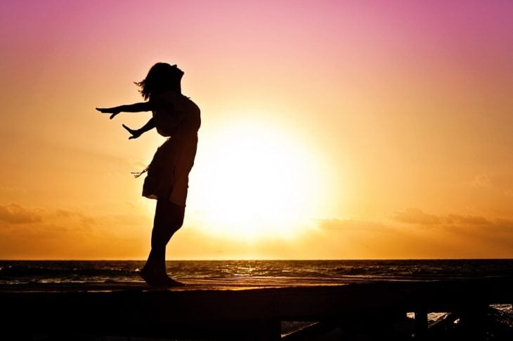 chica feliz viendo el atardecer en el mar