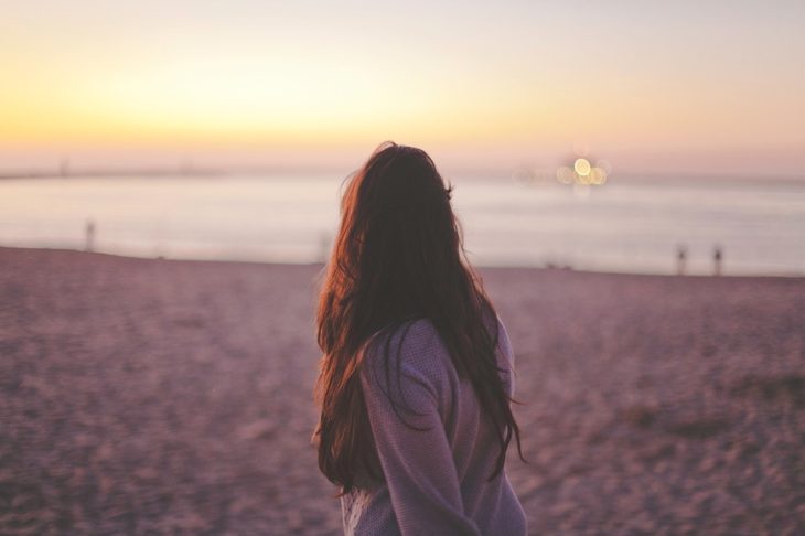 chica mirando el mar desde la playa