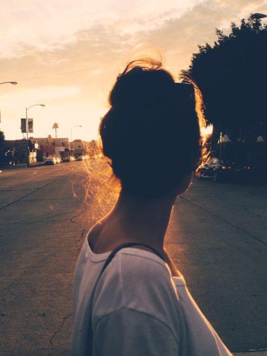 Chica observando el atardecer en la ciudad