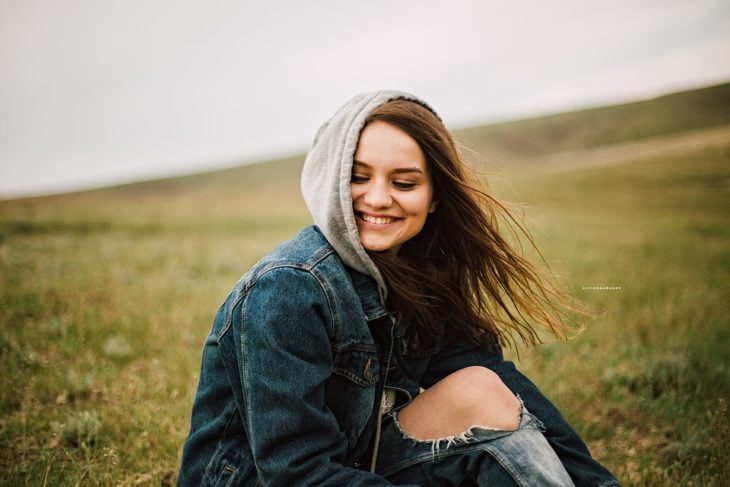 chica sonriendo contra el viento en el campo