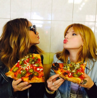 dos chicas comiendo pizza muy condimentada