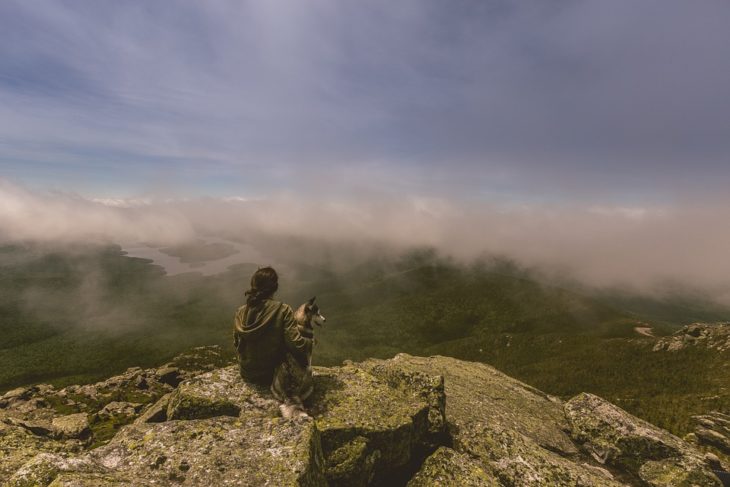 mujer con su perro frente a un paisaje