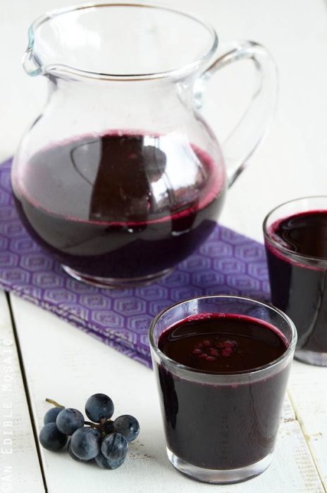 una jarra y dos vasos de jugo de uva