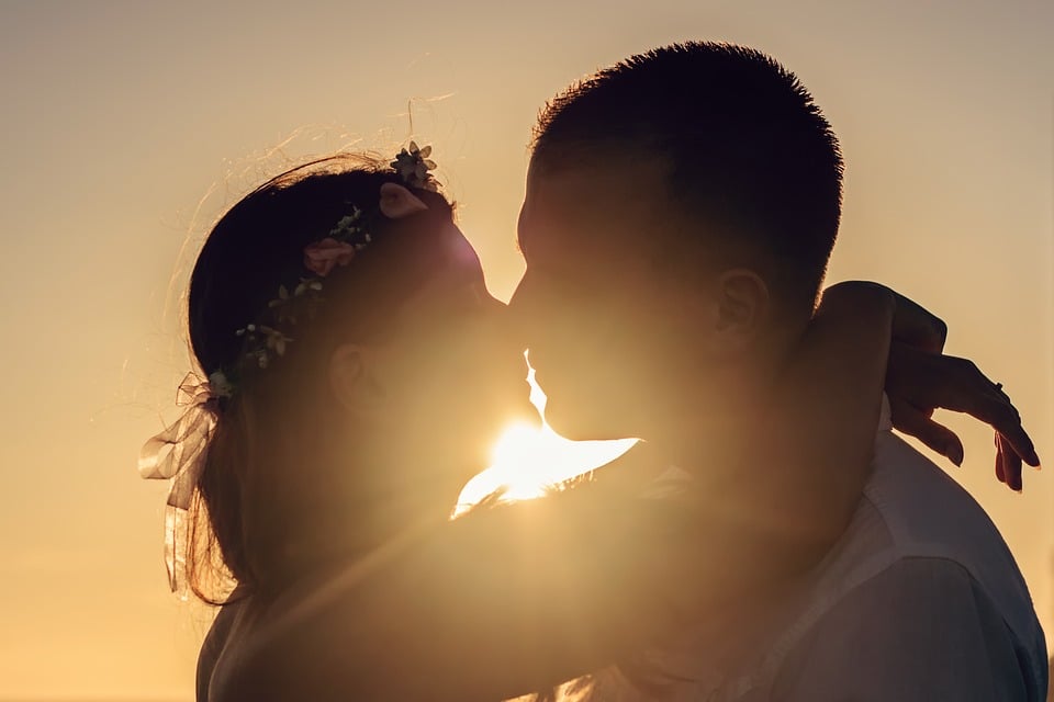 pareja besandose contra la luz del sol